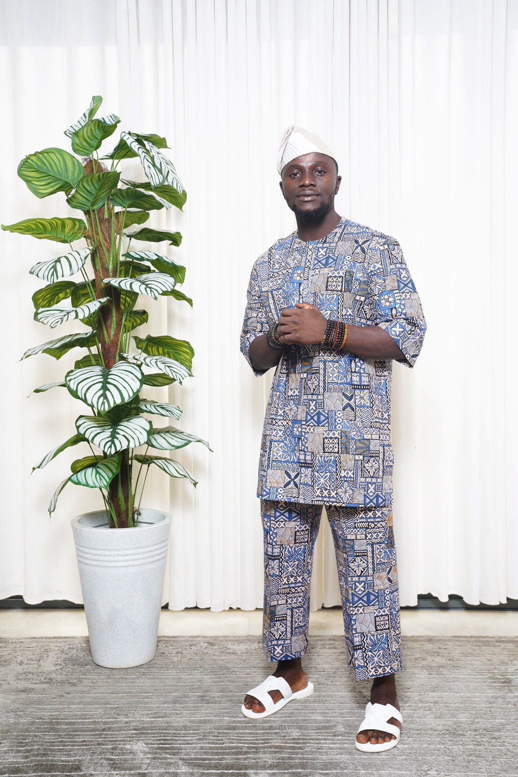 Blue African geometric print top and trousers styled with white headwrap and sandals