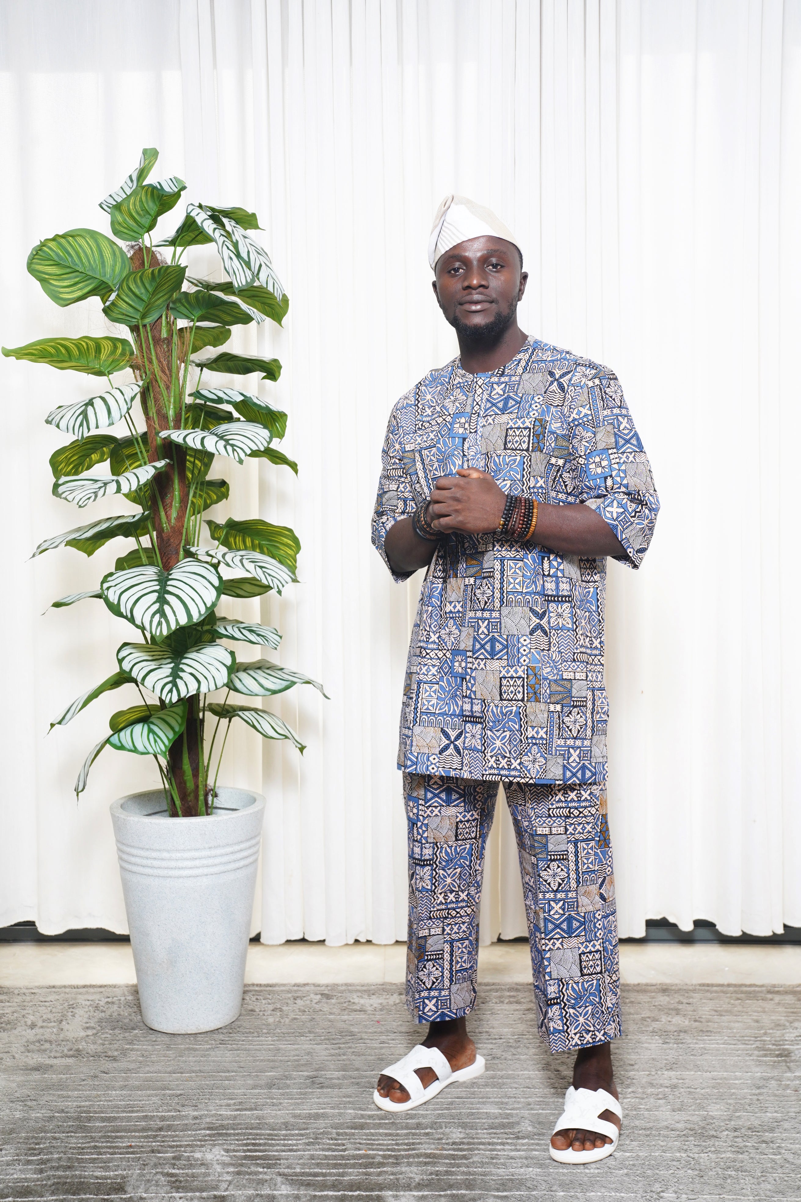 Blue African geometric print top and trousers styled with white headwrap and sandals