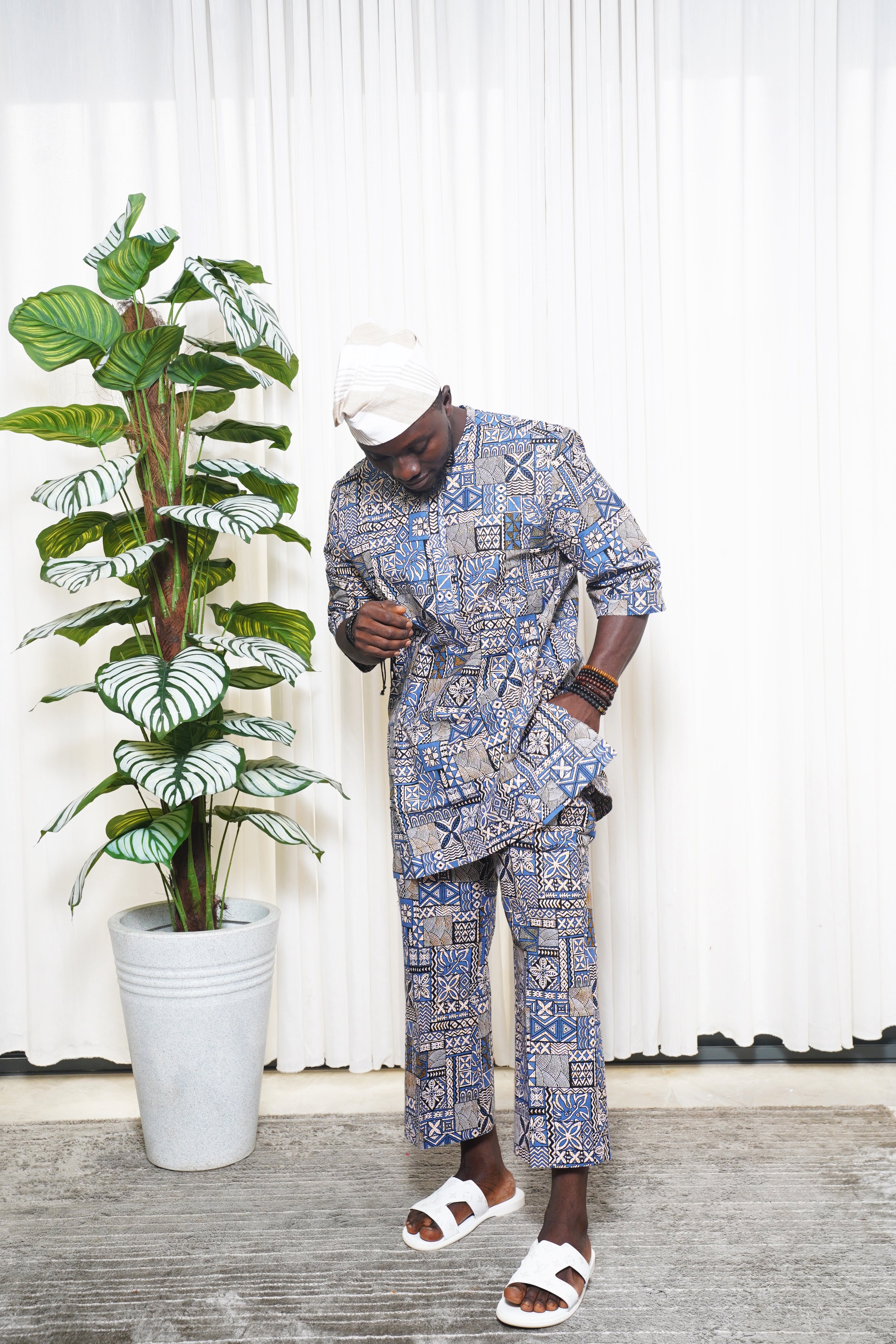 Blue African geometric print top and trousers styled with white headwrap and sandals