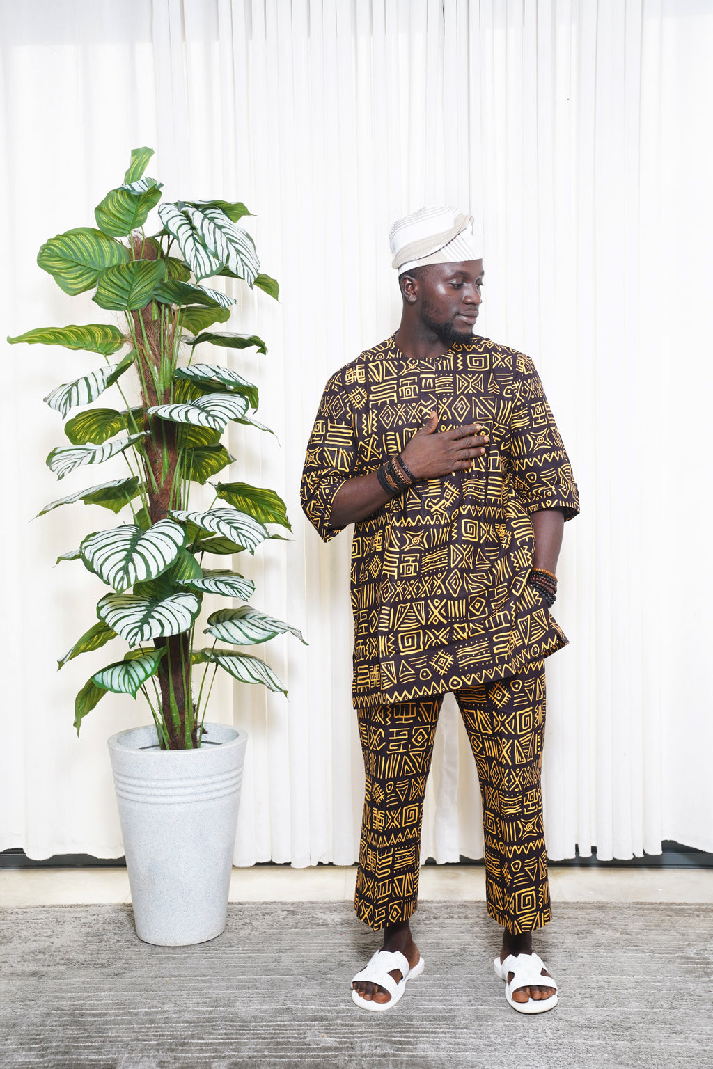 Black and yellow African geometric print top and trousers styled with white headwrap and sandals