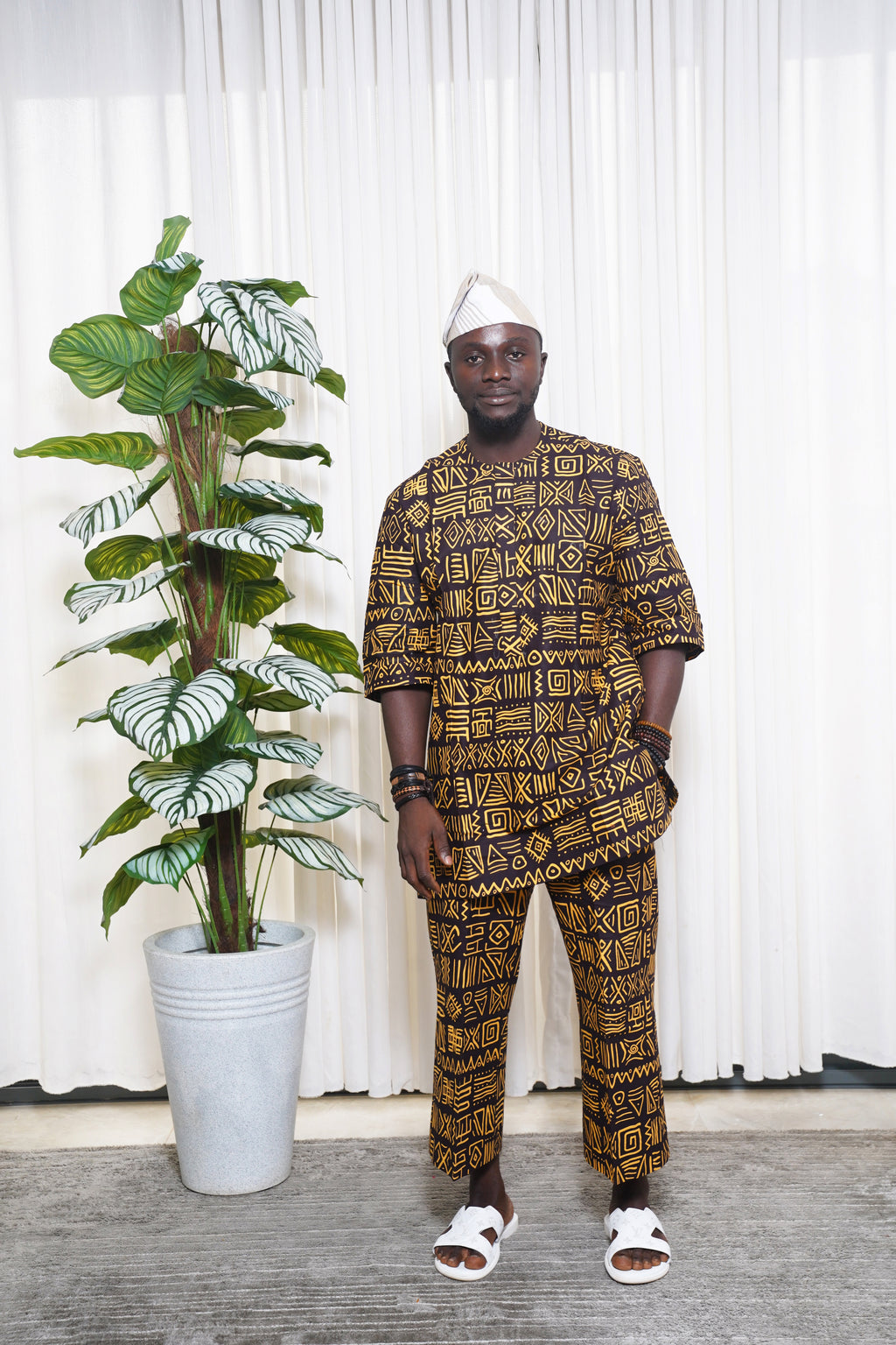 Black and yellow African geometric print top and trousers styled with white headwrap and sandals