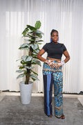 Model wearing black crop top with blue, brown, and beige African abstract print wide‑leg pants.