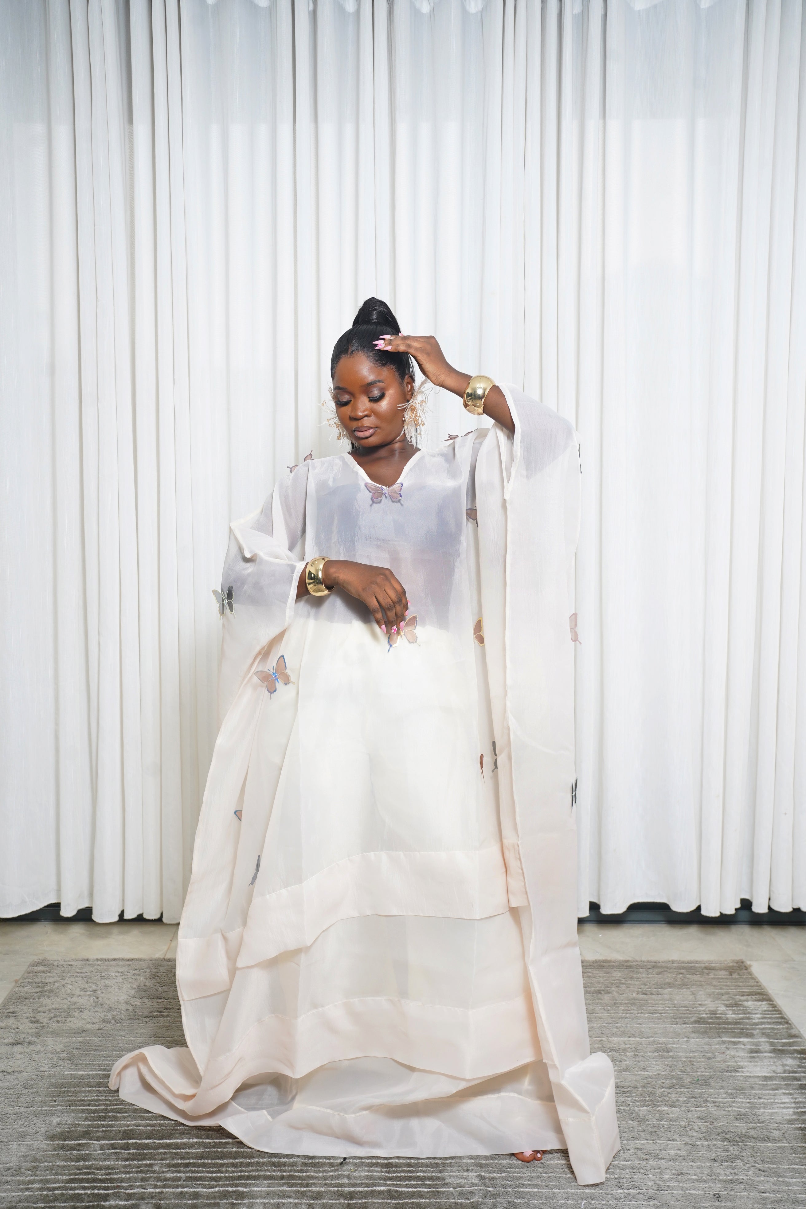 Cream sheer kaftan with butterfly embroidery and wide sleeves styled with gold accessories.”