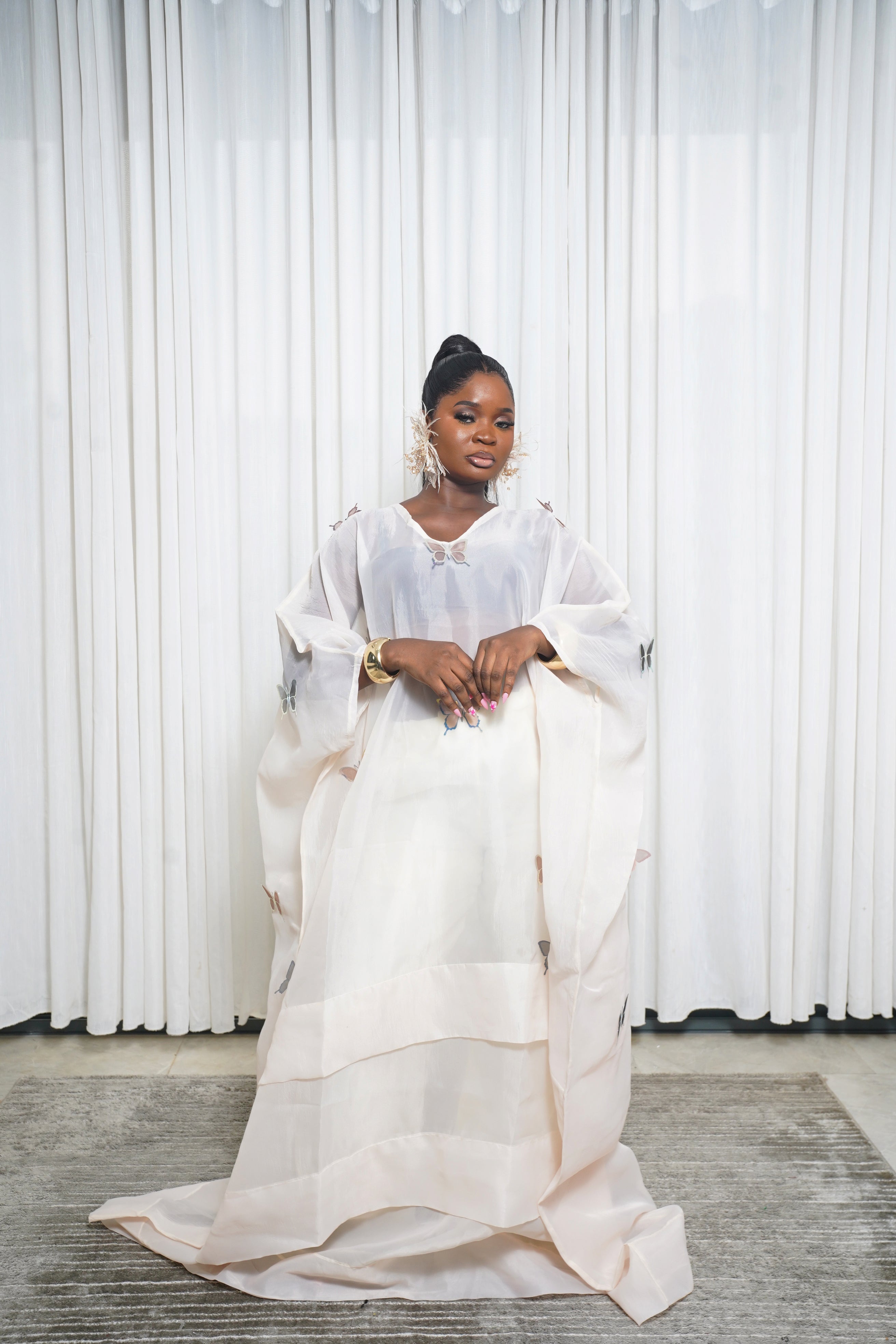 Cream sheer kaftan with butterfly embroidery and wide sleeves styled with gold accessories.”