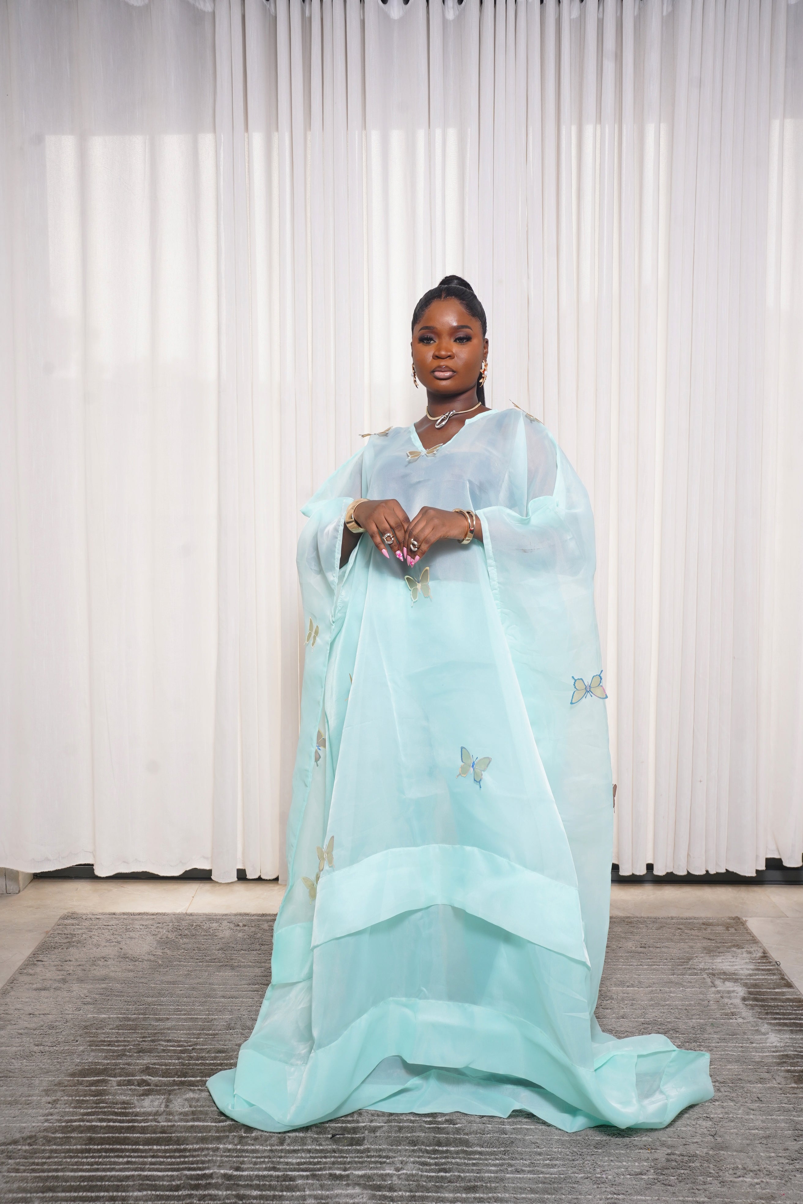 Flowing teal kaftan adorned with yellow‑green butterfly embroidery, styled with hoop earrings and necklace