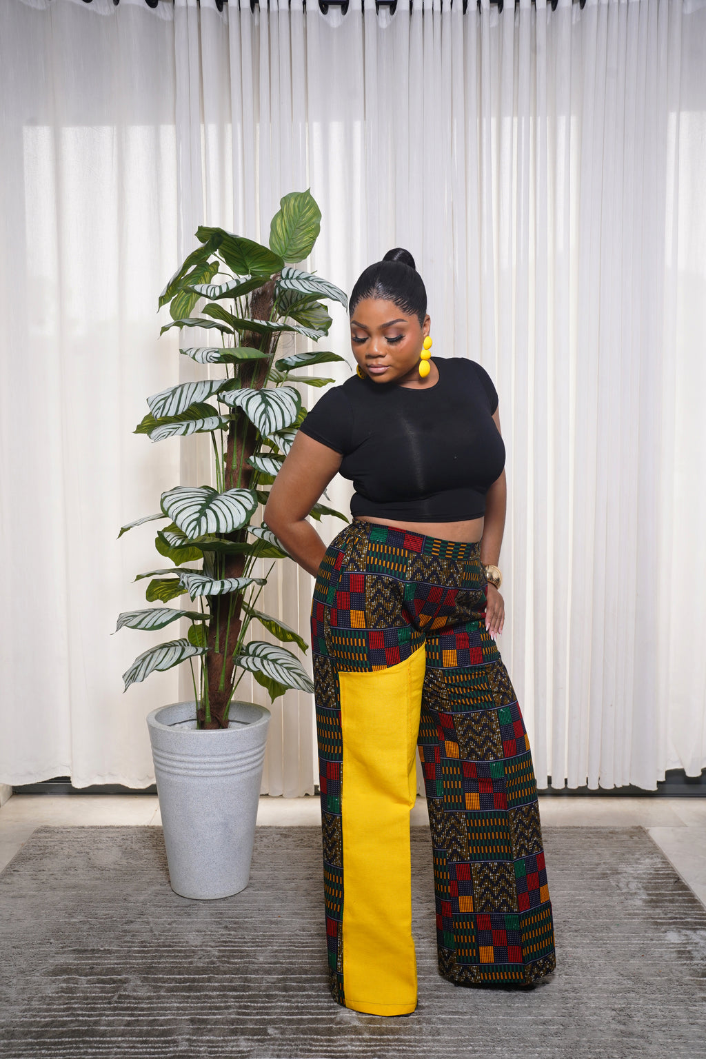 “Black crop top paired with multicolor African print wide‑leg pants featuring a bold yellow side panel.”