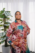 Model wearing red and maroon African abstract print shirt and pants with gold accessories